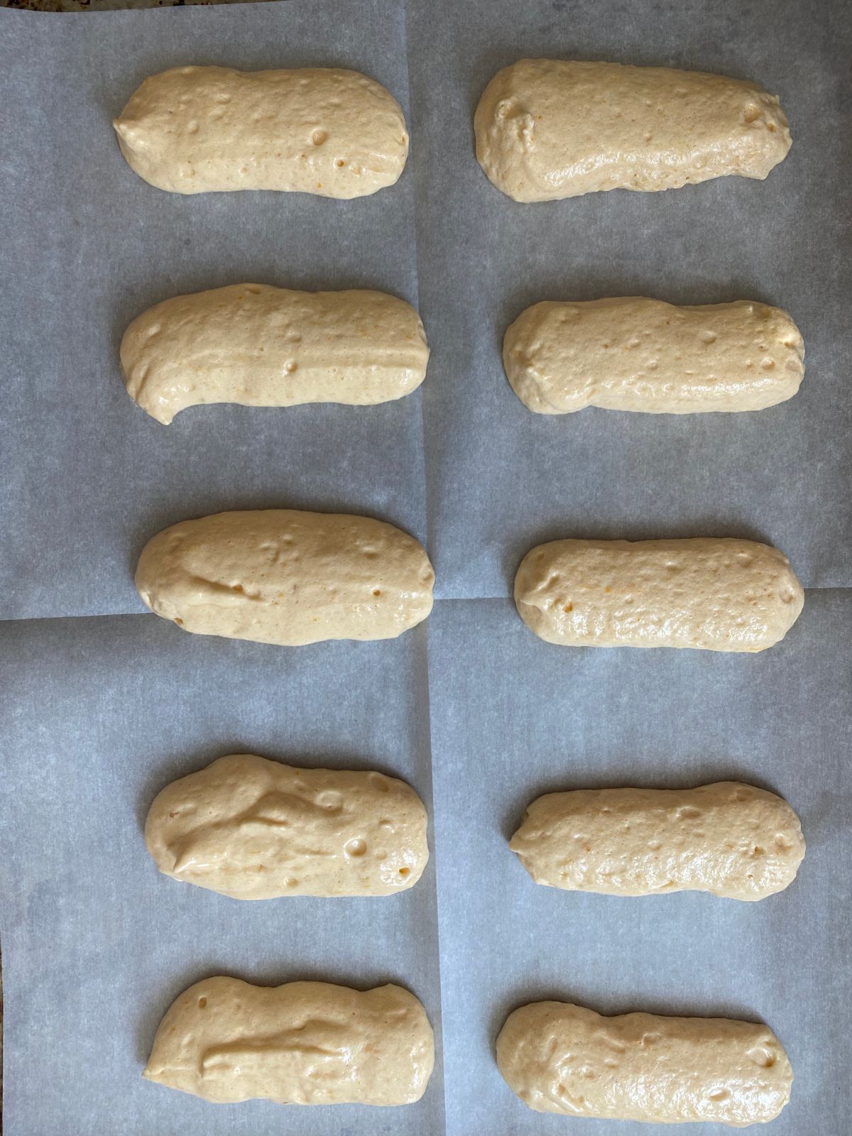 Ladyfingers piped onto a baking pan. 