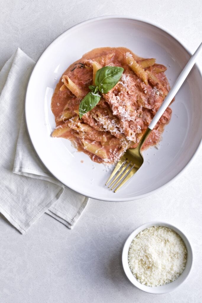 Penne in pink sauce on a plate with a fork in it.