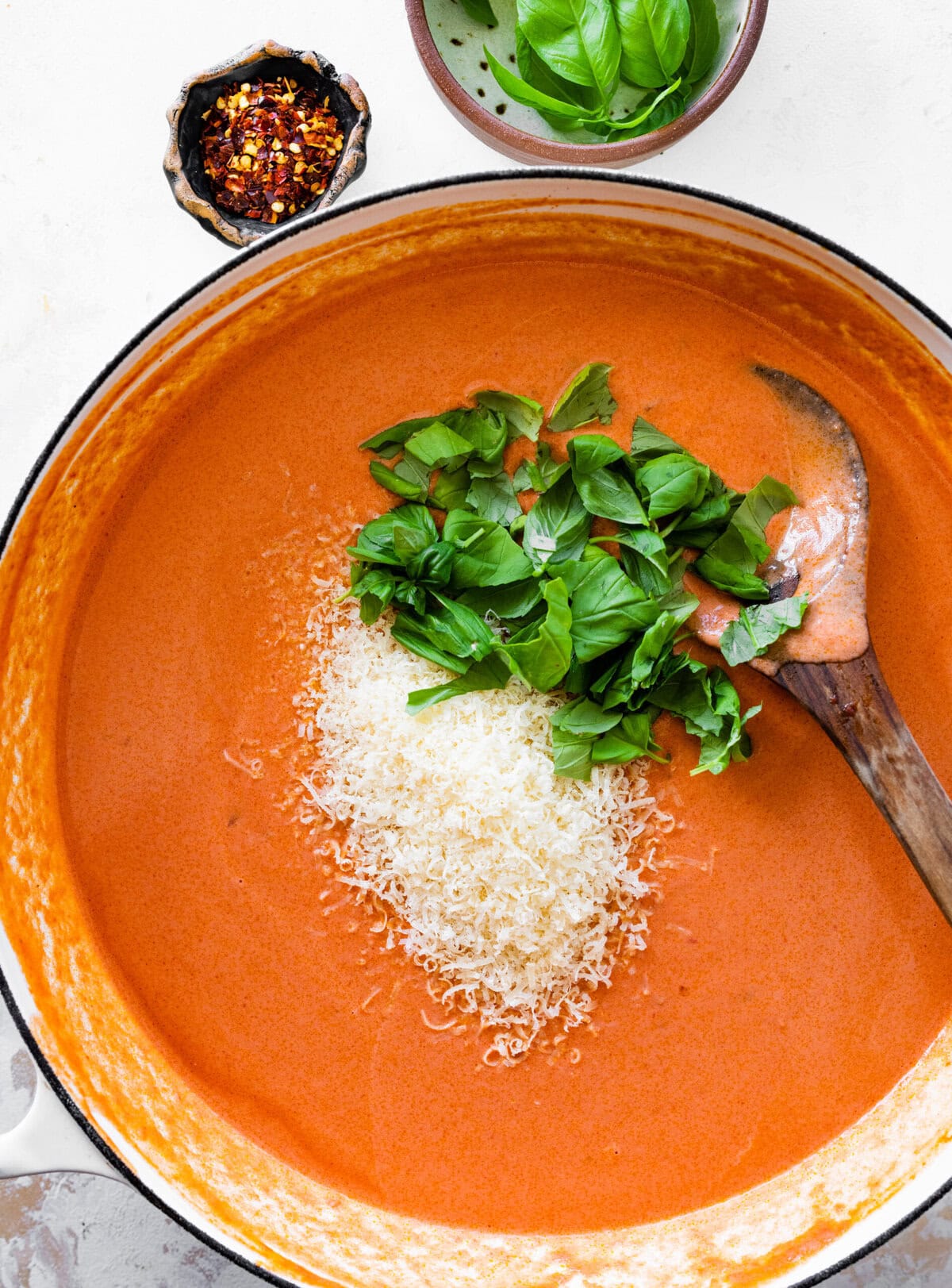 Fresh parmigiano cheese in the pan with the pink sauce and fresh basil.