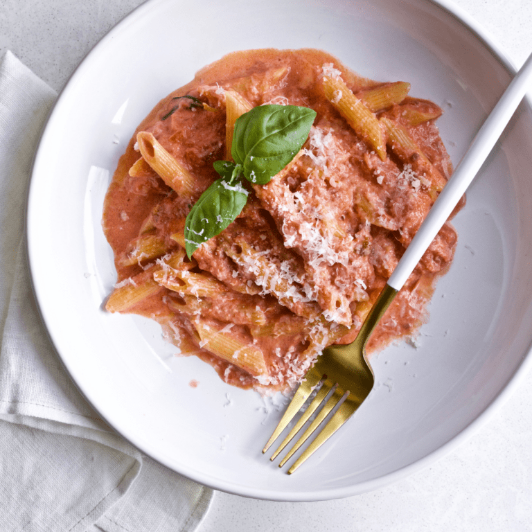 Penne in pink sauce on a plate with a fork in it.
