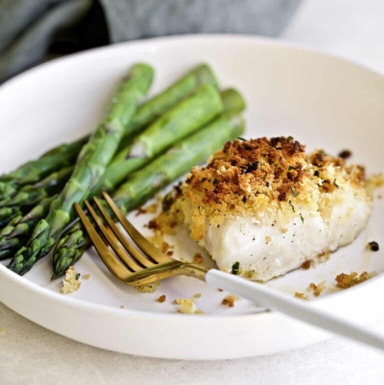 Crispy Baked Cod with Panko Recipe on a plate with a side of steamed asparagus