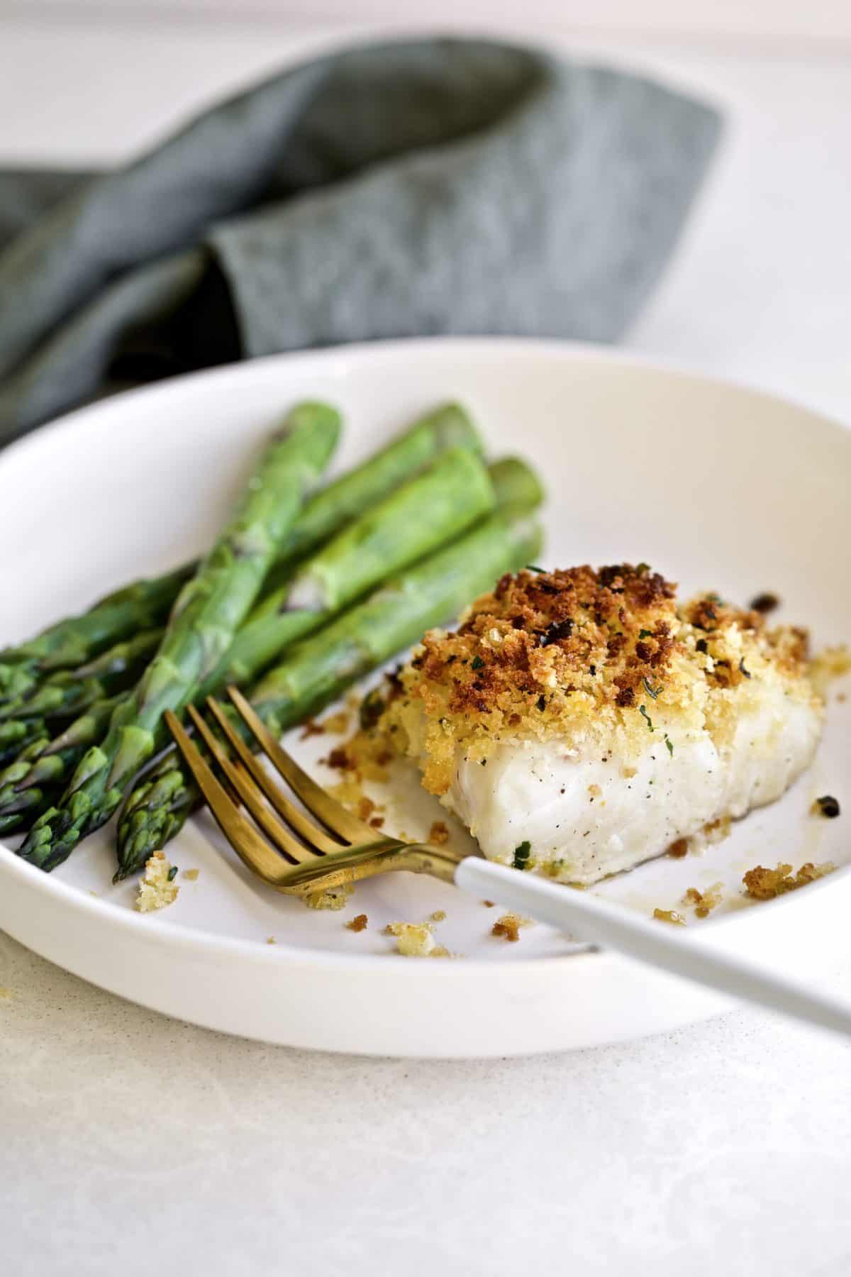 Crispy Baked Cod with Panko Recipe on a plate with a side of steamed asparagus 