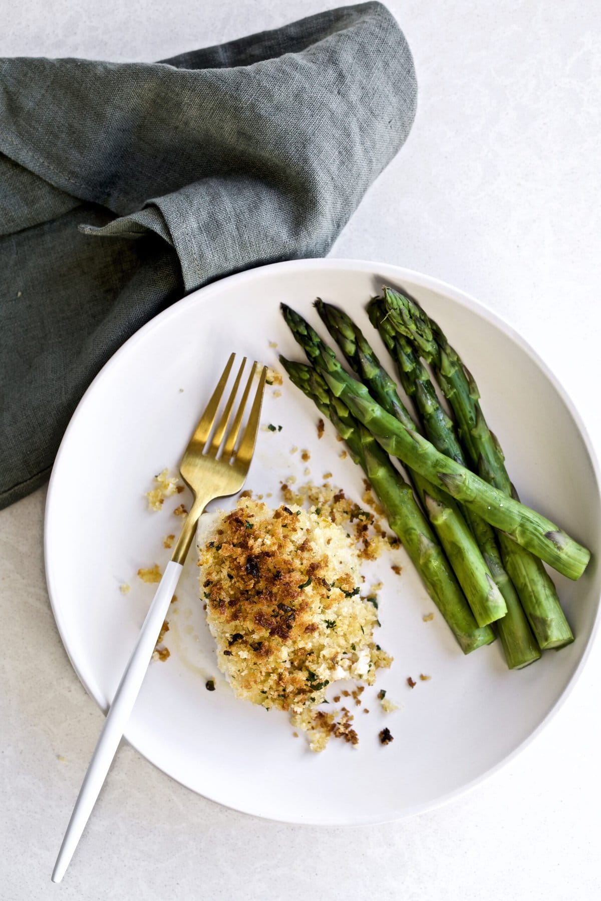 Crispy Baked Cod with Panko Recipe on a plate with a side of steamed asparagus