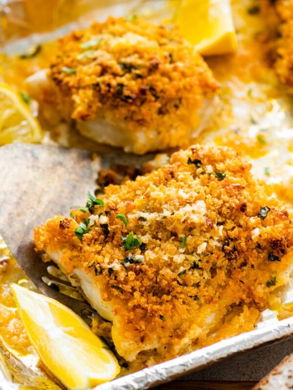 baked cod with panko after baking on the baking sheet. Lemons on the tray.