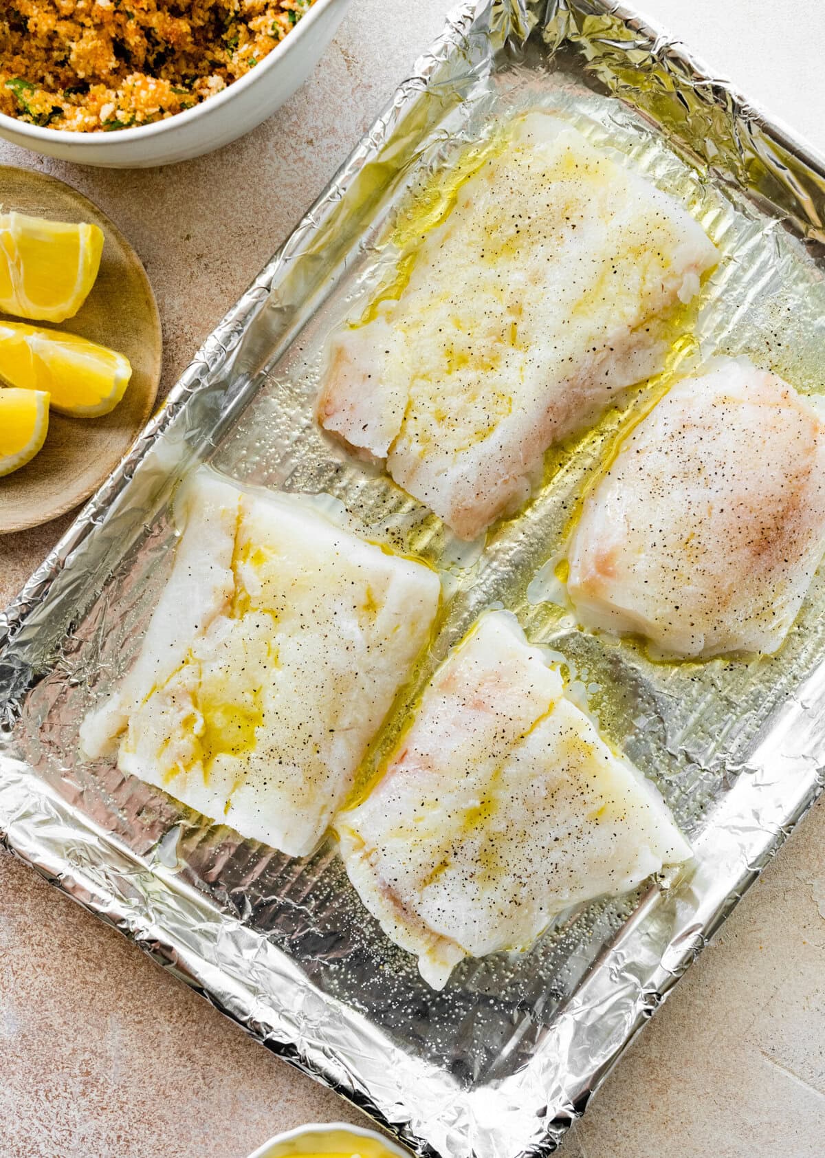 cod on a baking sheet with tin foil on it. Olive oil on the cod.