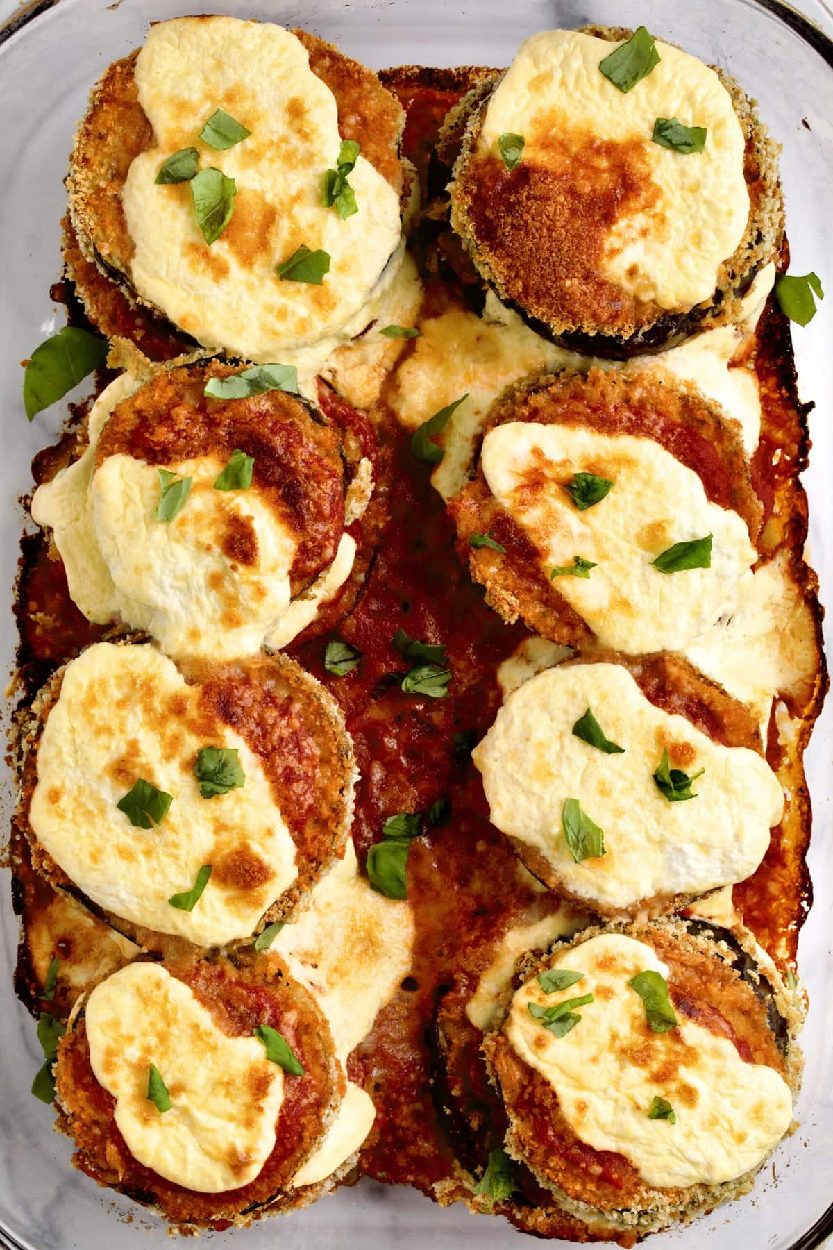 baked eggplant slices in a baking dish ready to serve. 