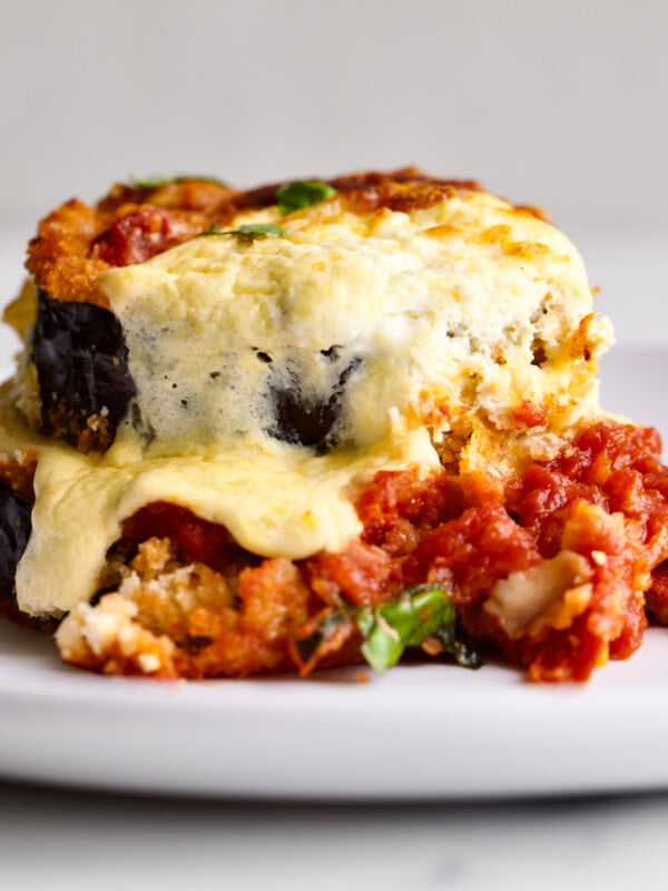 baked eggplant on a plate with extra tomato sauce on the plate.