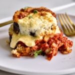 baked eggplant slice on a plate with fork and knife.