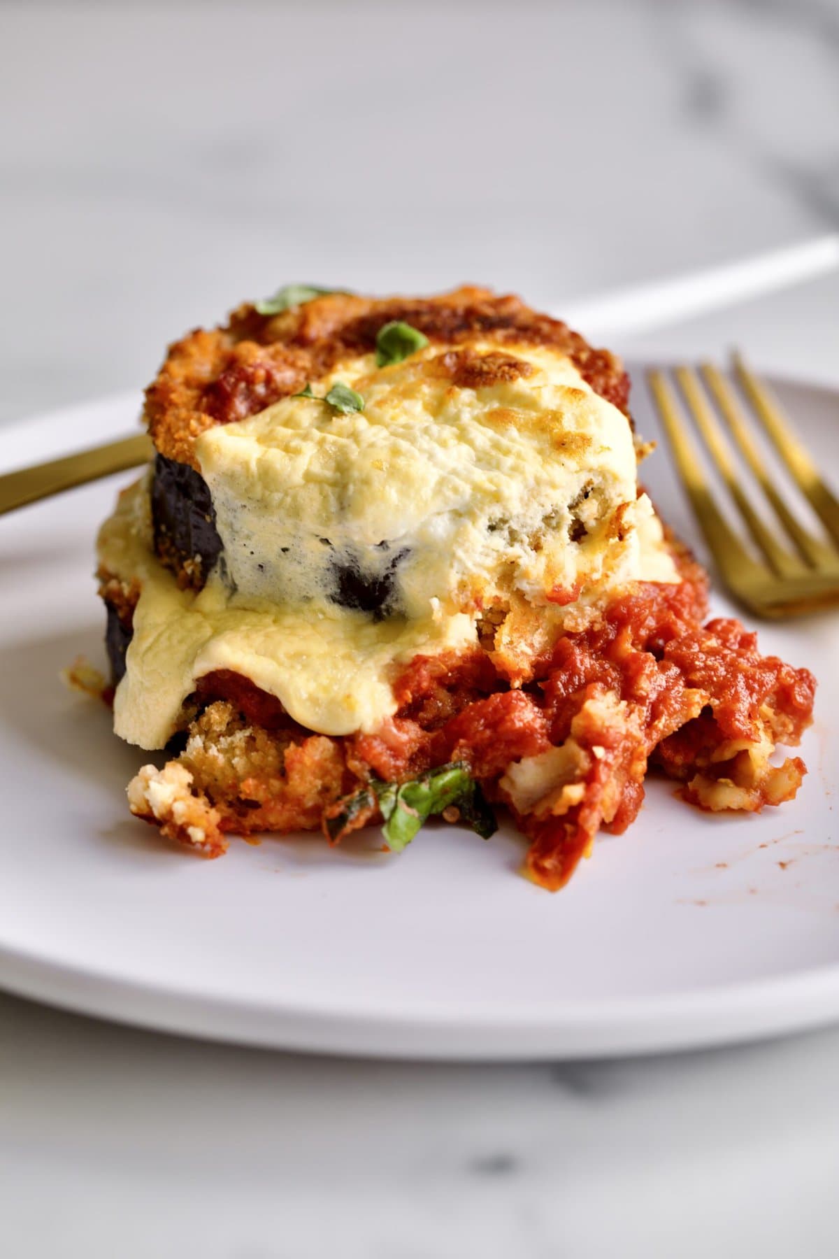 baked eggplant slice on a plate with fork and knife.
