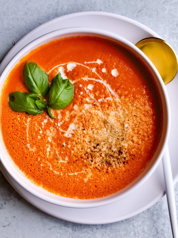 tomato soup in bowl with spoon on a plate.