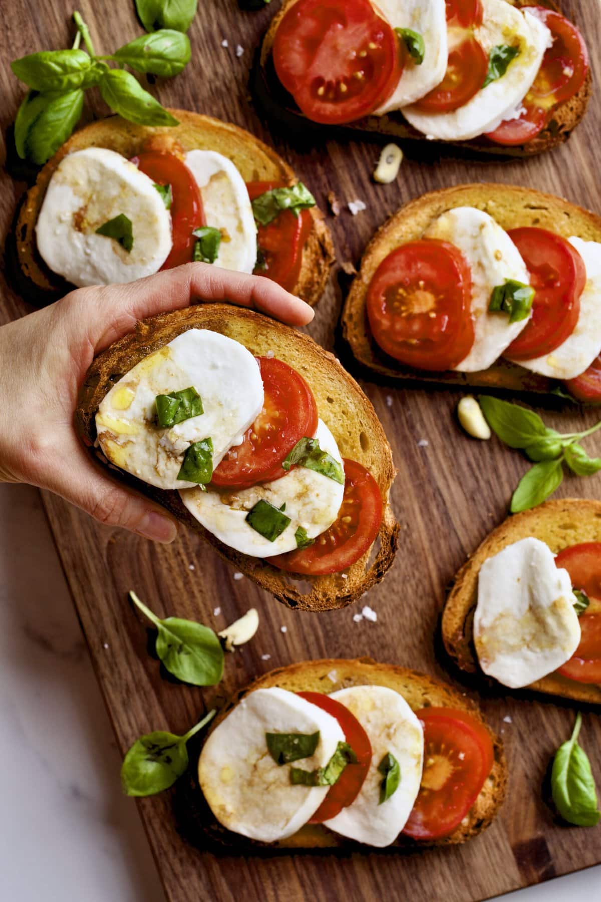 Easy Bruschetta Recipe with Mozzarella and Tomato Basil hand holding one.