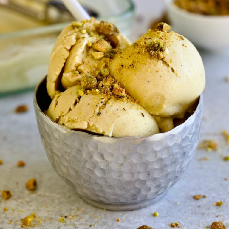 pistachio ice cream in metal bowl with spoon.