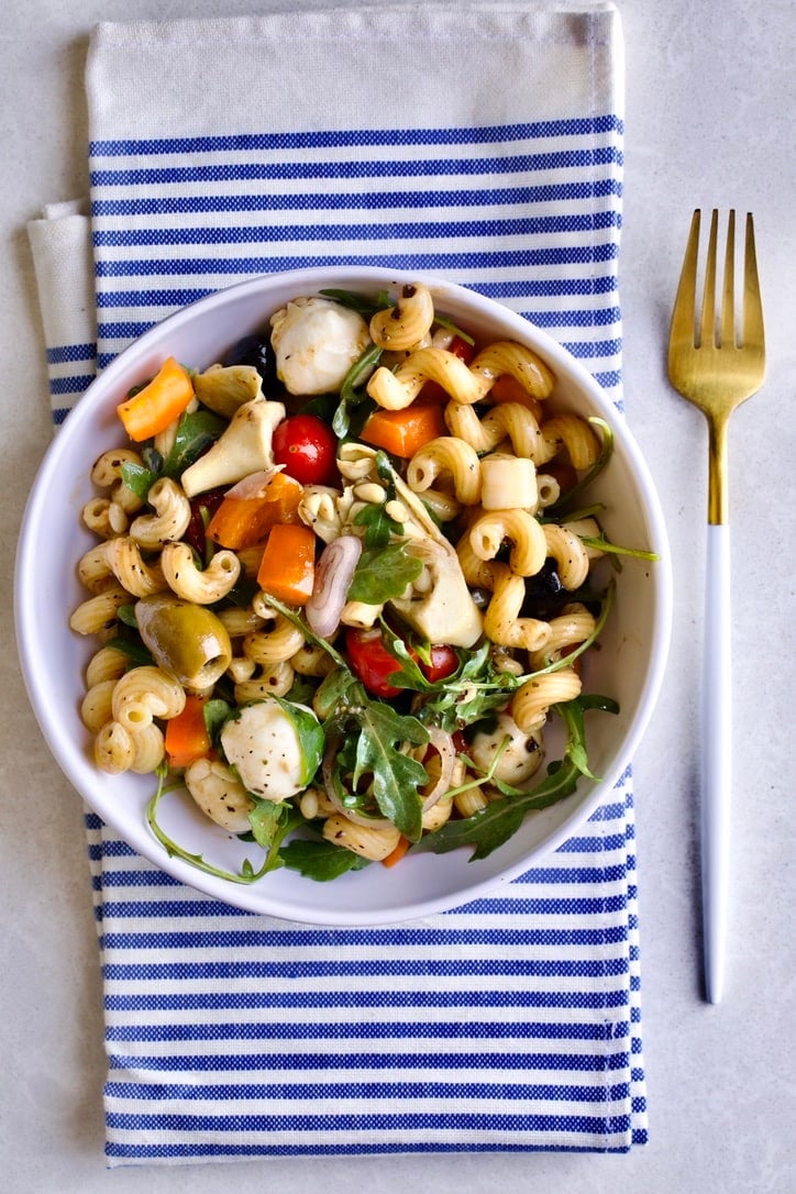 bowl of antipasto pasta salad with a napkin and fork. 