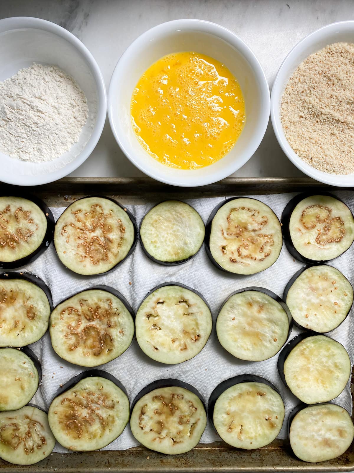 dipping the eggplant slices in eggs and breadcrumb mixture.