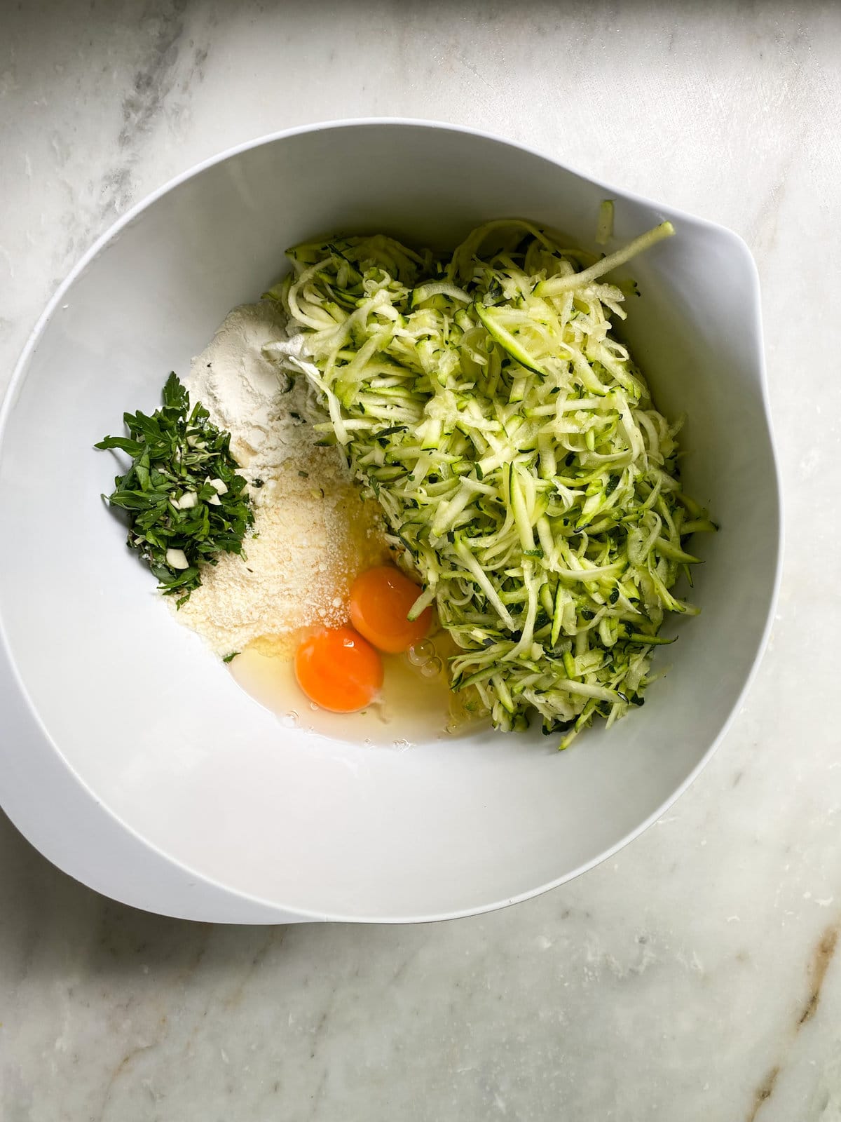 mixing zucchini fritter ingredients in a bowl