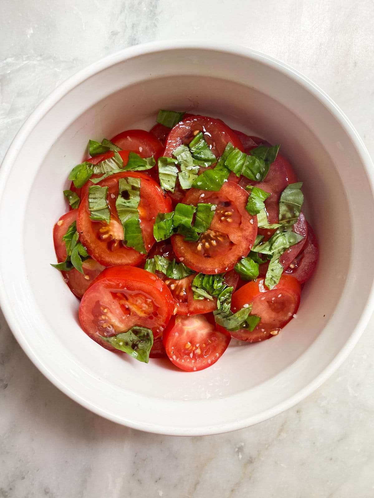 tomatoes marinating in olive oil and balsamic vinegar with basil