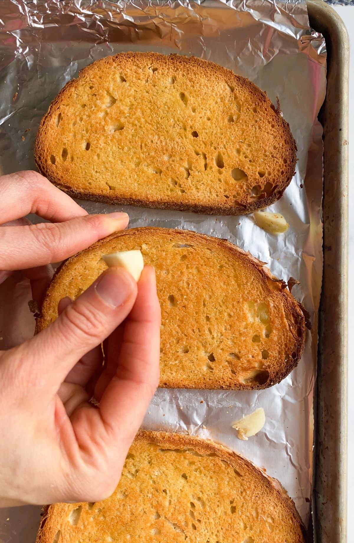 rubbing garlic on toasted bread.