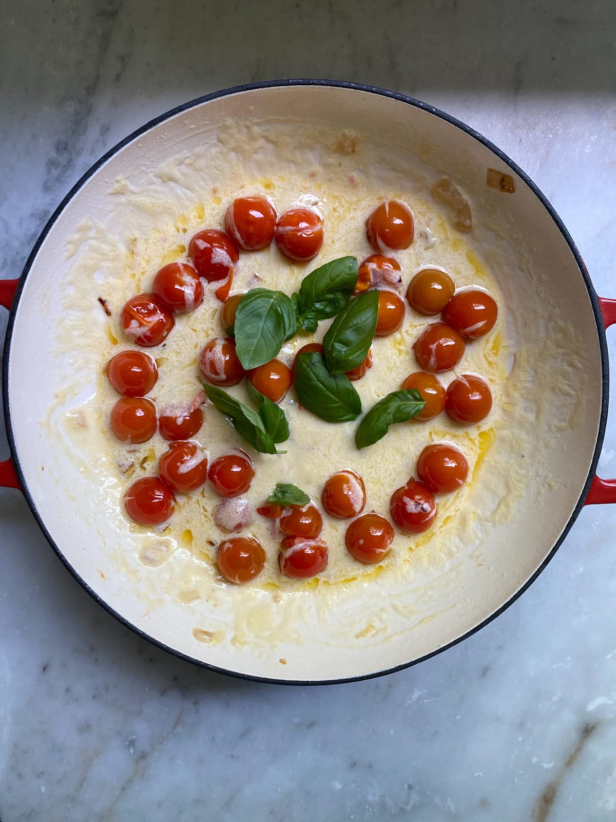 process shot. adding mascarpone cheese to the pan with cooked tomatoes