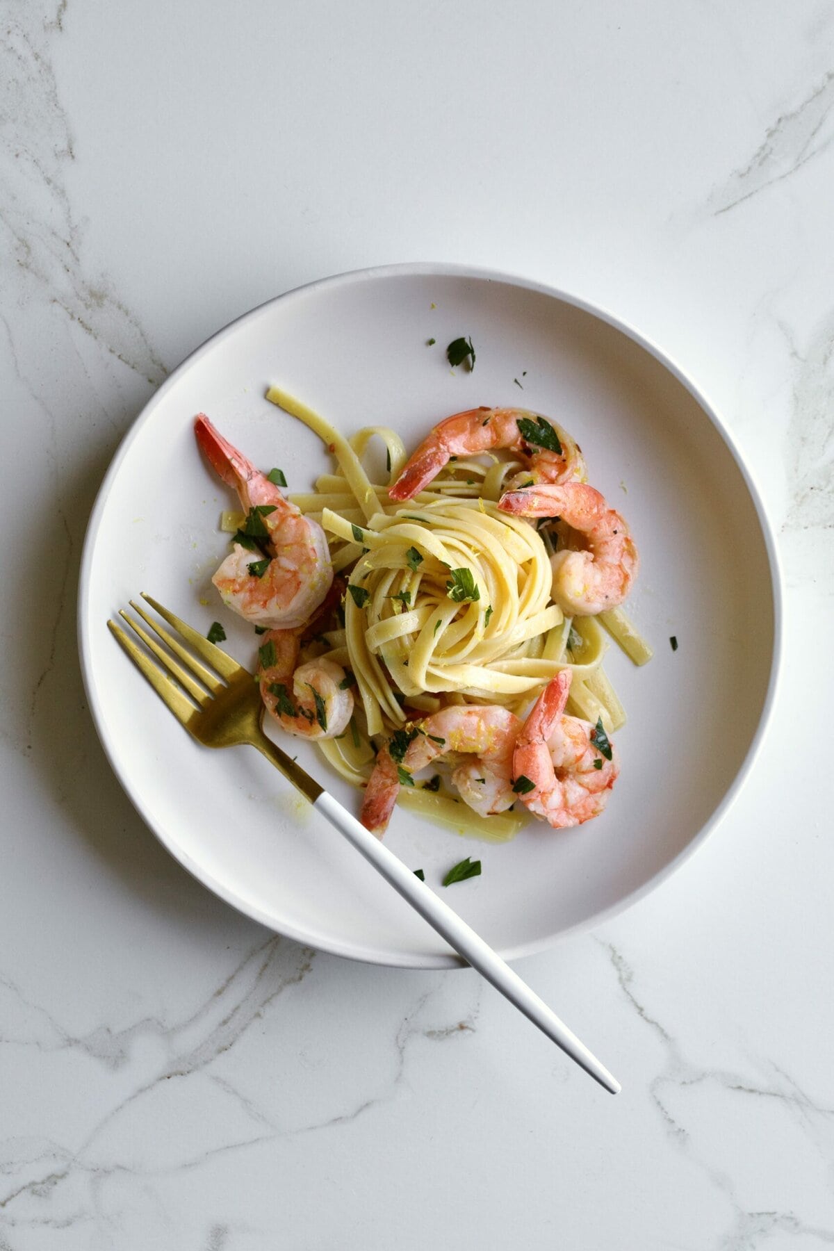 shrimp scampi fettuccine on a plate with parsley and a fork.