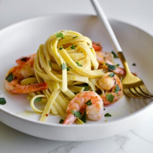 Shrimp scampi pasta on a plate with parsley and a fork.