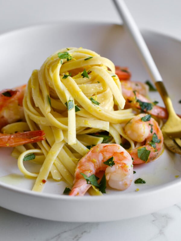 shrimp scampi fettuccine on a plate with parsley and a fork.