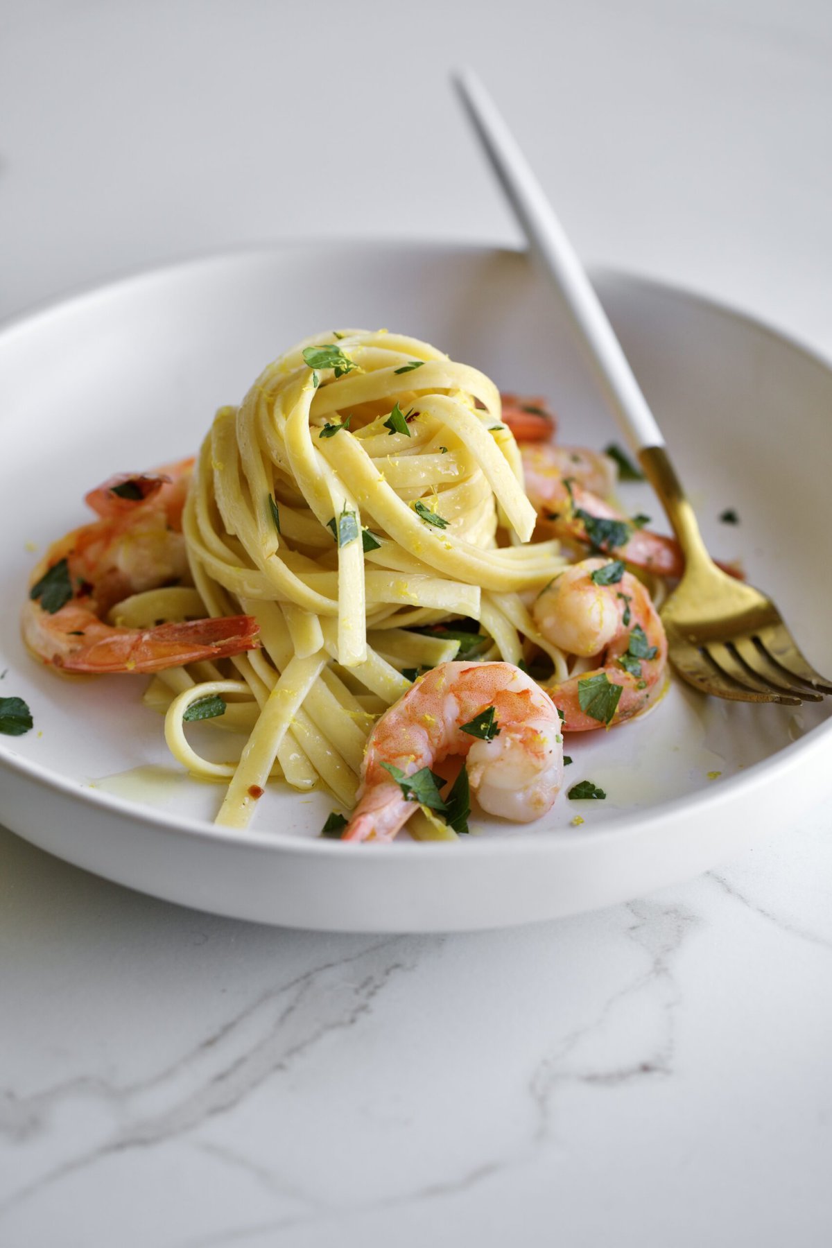 shrimp scampi fettuccine on a plate with parsley and a fork.