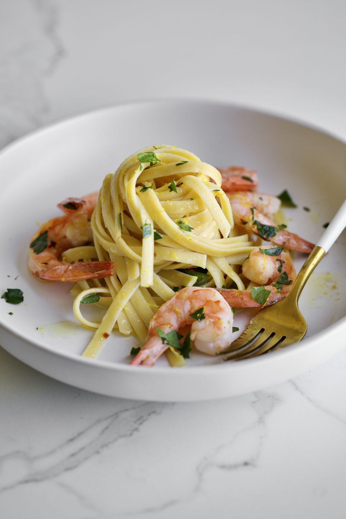 shrimp scampi fettuccine on a plate with parsley and a fork.