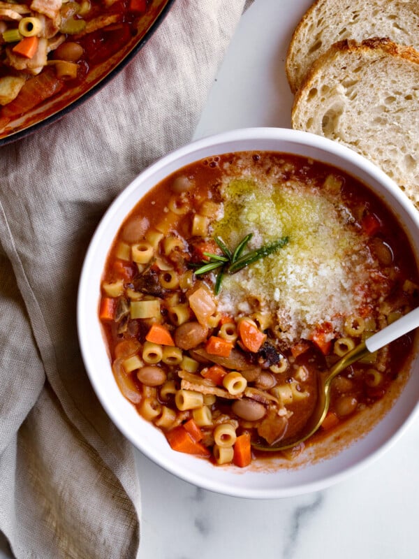 bowl of soup in bowl with spoon and side of bread.