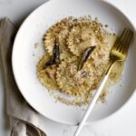 Butternut squash ravioli with sage butter sauce on a plate with a fork.