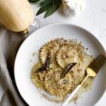Fork on a plate of butternut squash ravioli with sage butter sauce.