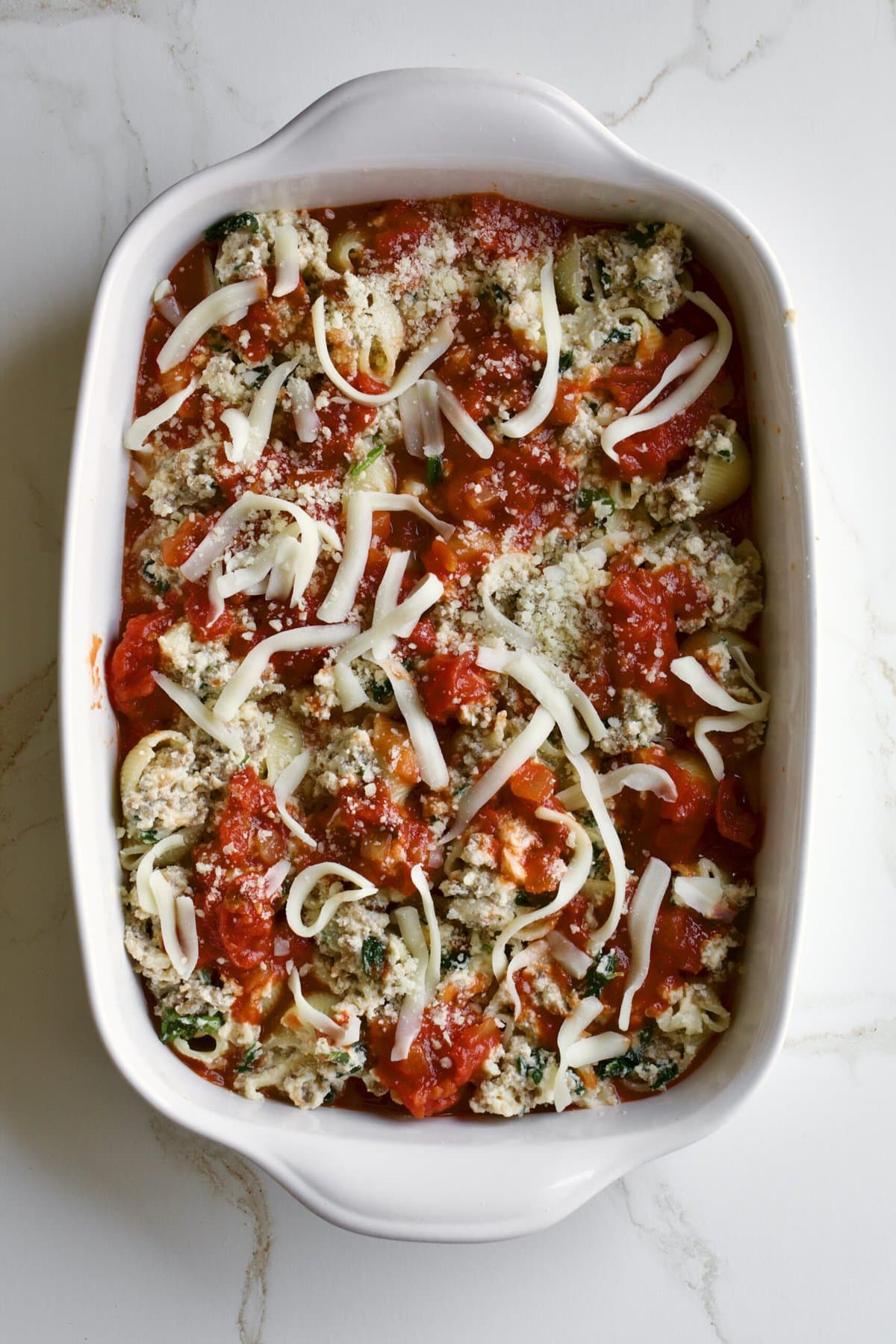 stuffed shells covered in red sauce ready to bake.