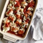 stuffed shells covered in red sauce ready to bake. Smaller baking dish to freeze.