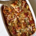 Baked stuffed shells with melted cheese and a wooden spoon.