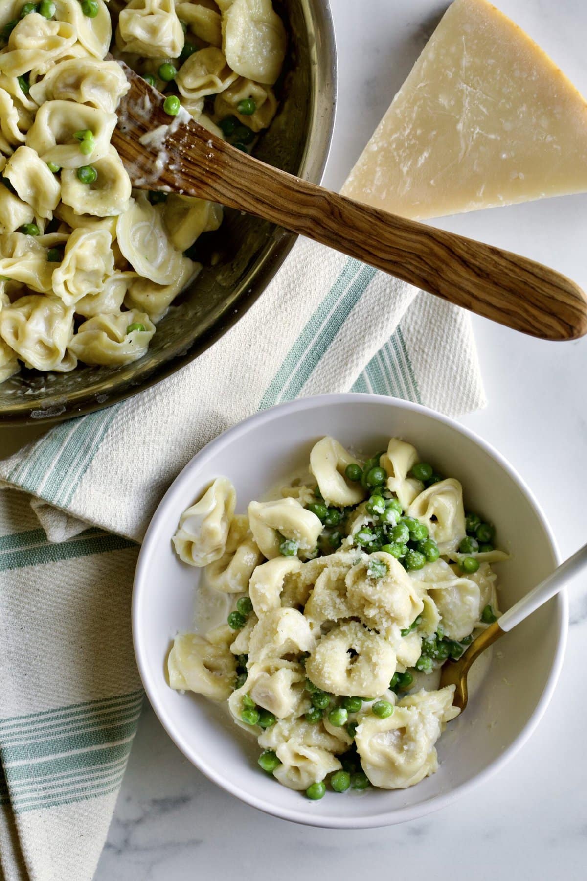 bowl of pasta with skillet and serving spoon in the background.