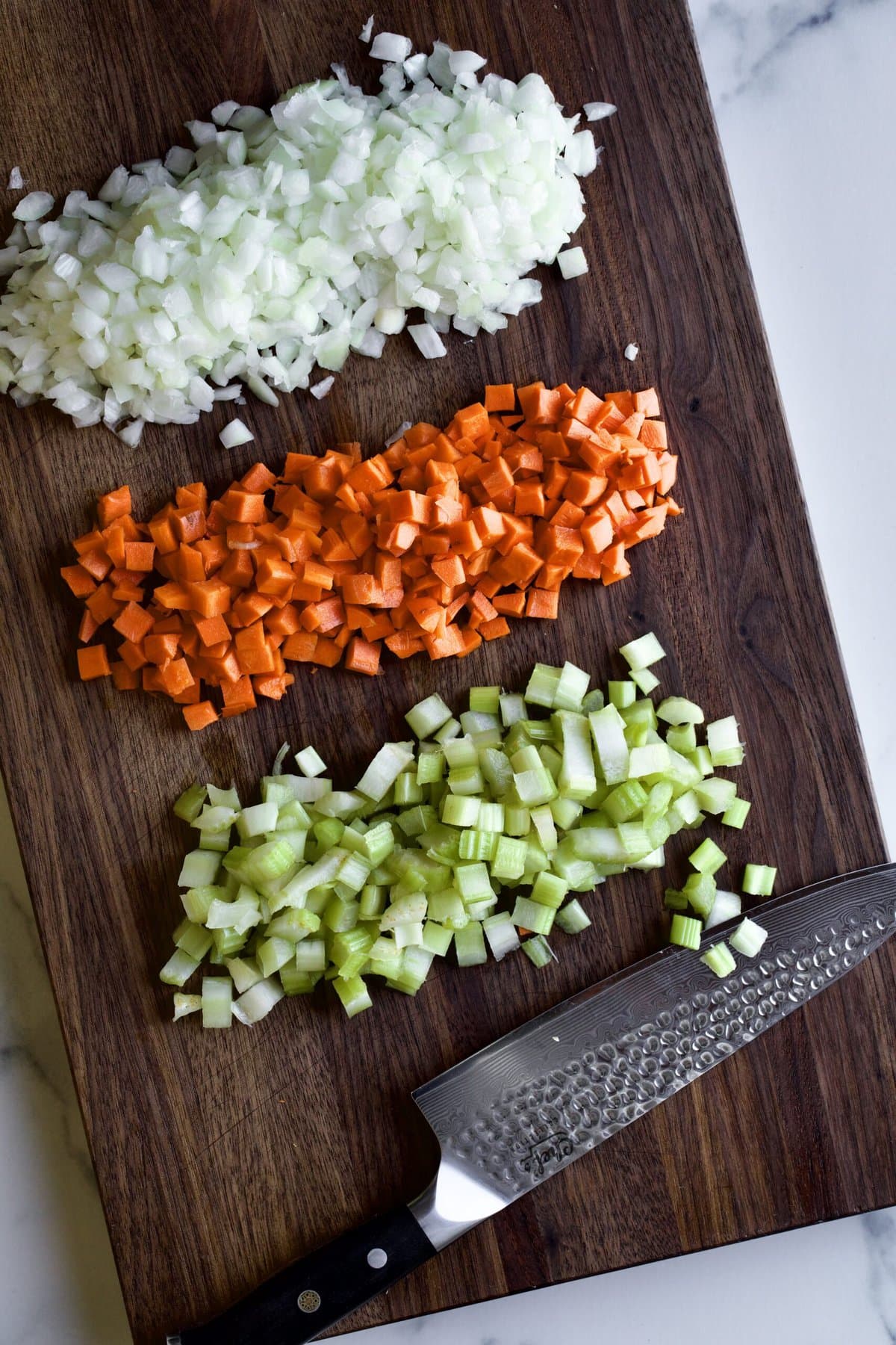 diced ingredients for soffritto on wooden cutting board.