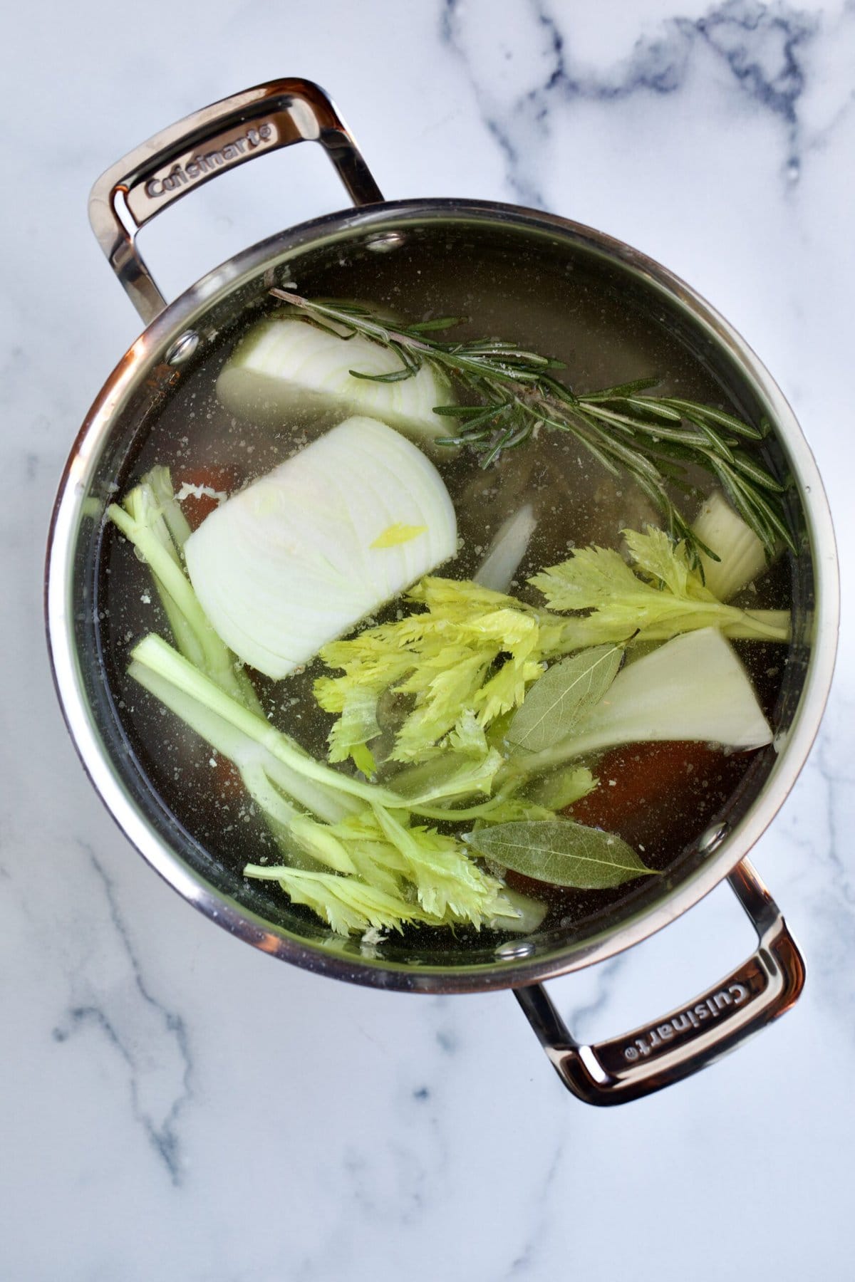 filling pot with water and ingredients to make chicken broth.