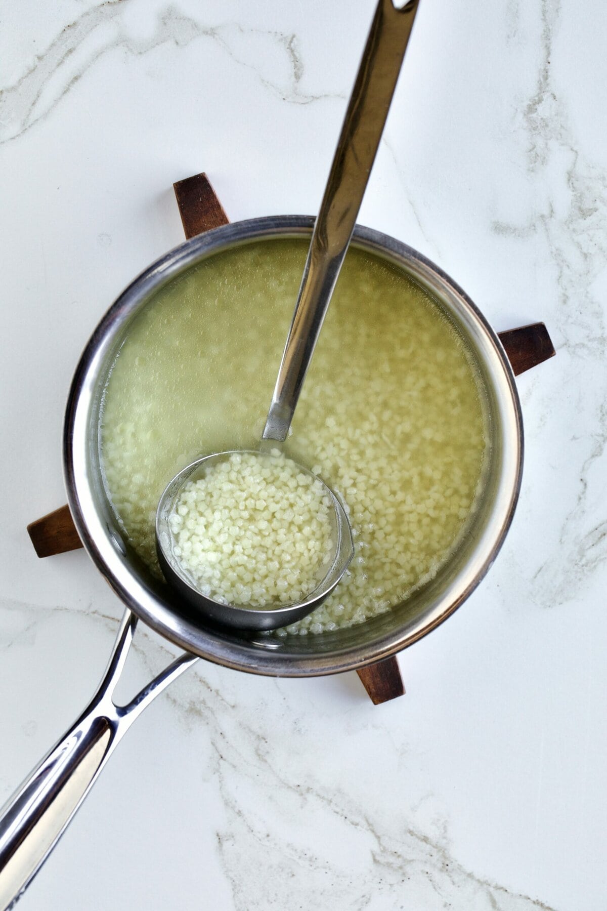 pastina soup in a soup pot with ladle.