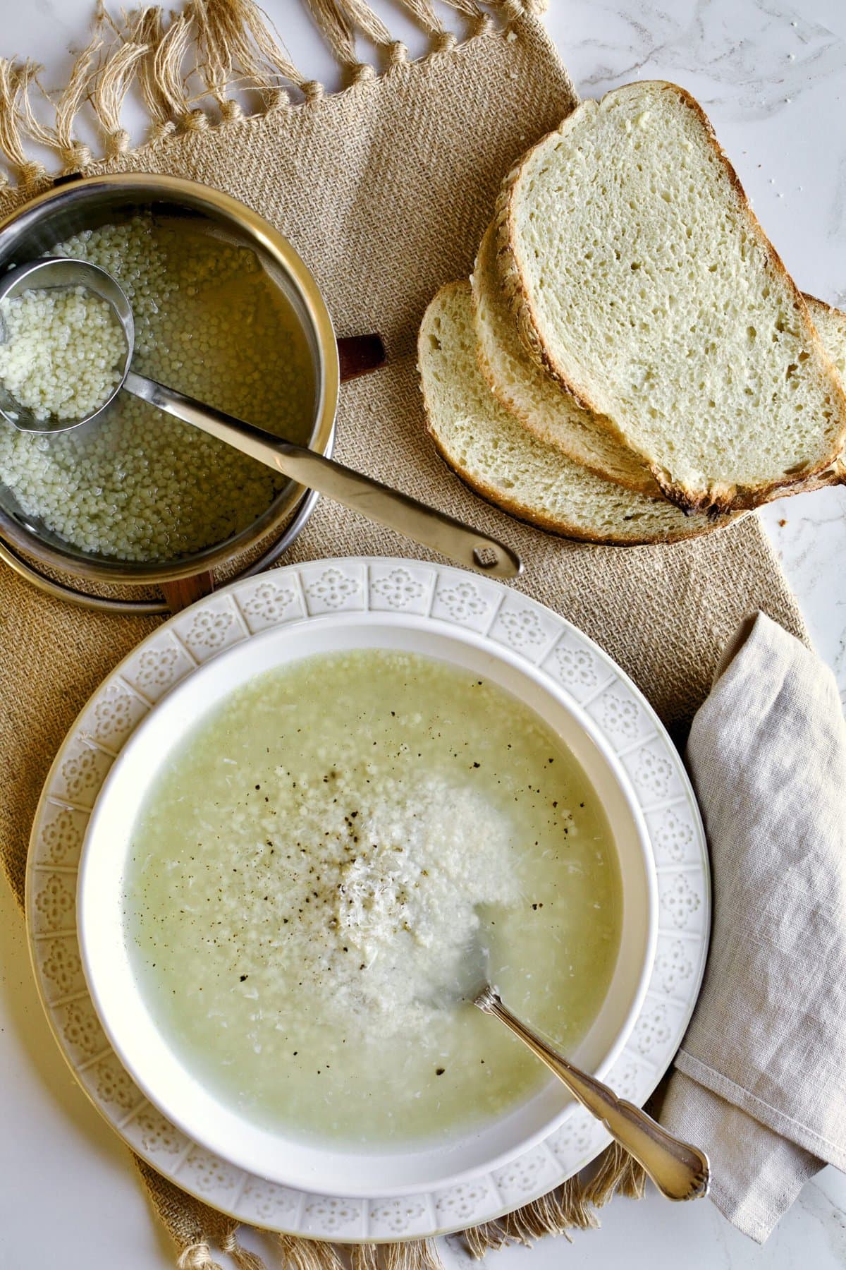 pastina soup in a bowl with spoon and bread.