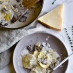 ravioli in cream sauce on a plate with the pan in the background.