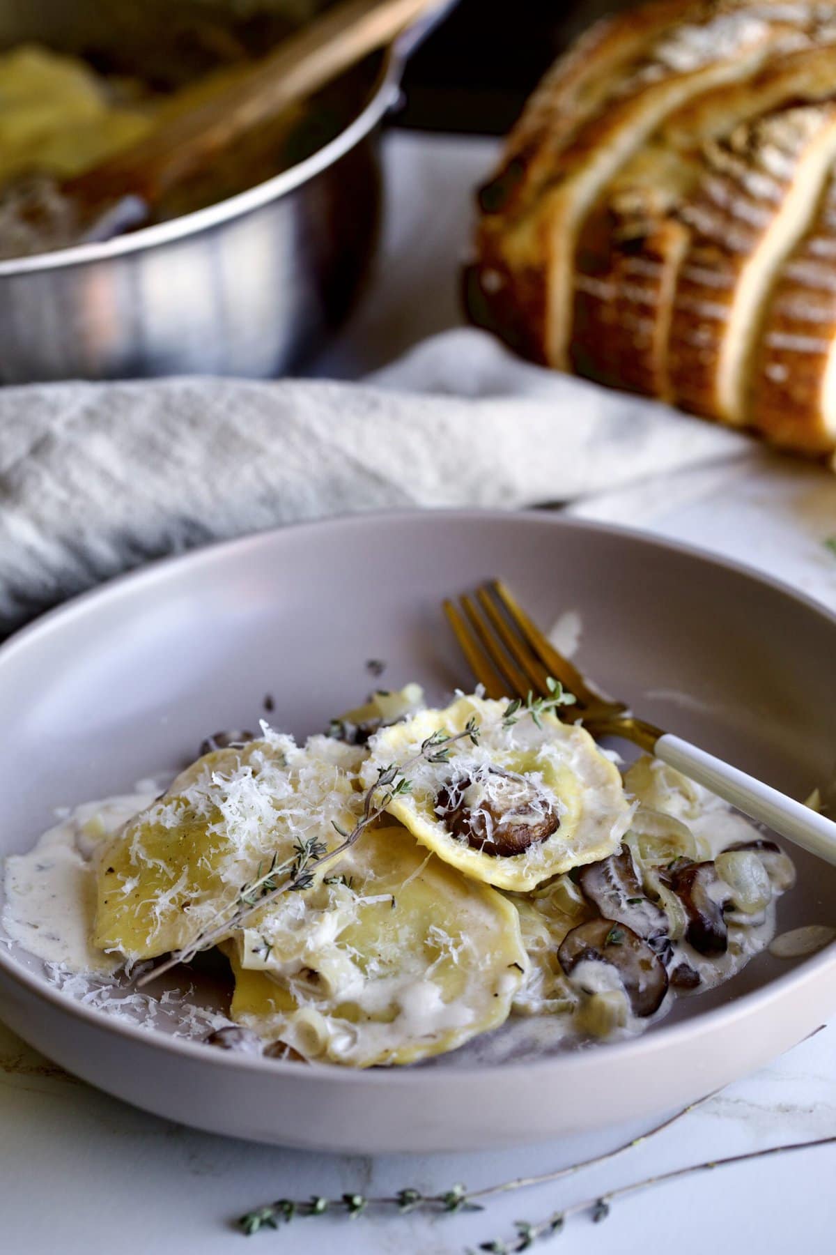 plated ravioli in cream sauce with rosemary as garnish. 