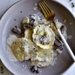 close up of plated ravioli in cream sauce with fork on the plate.