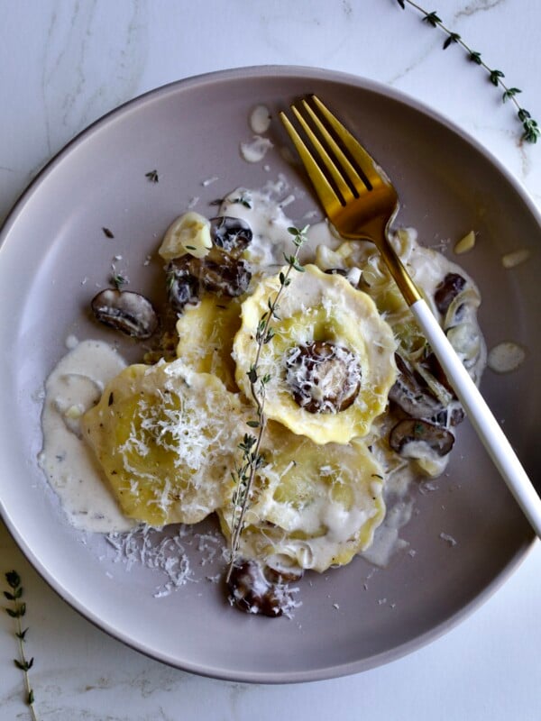 close up of plated ravioli in cream sauce with fork on the plate.