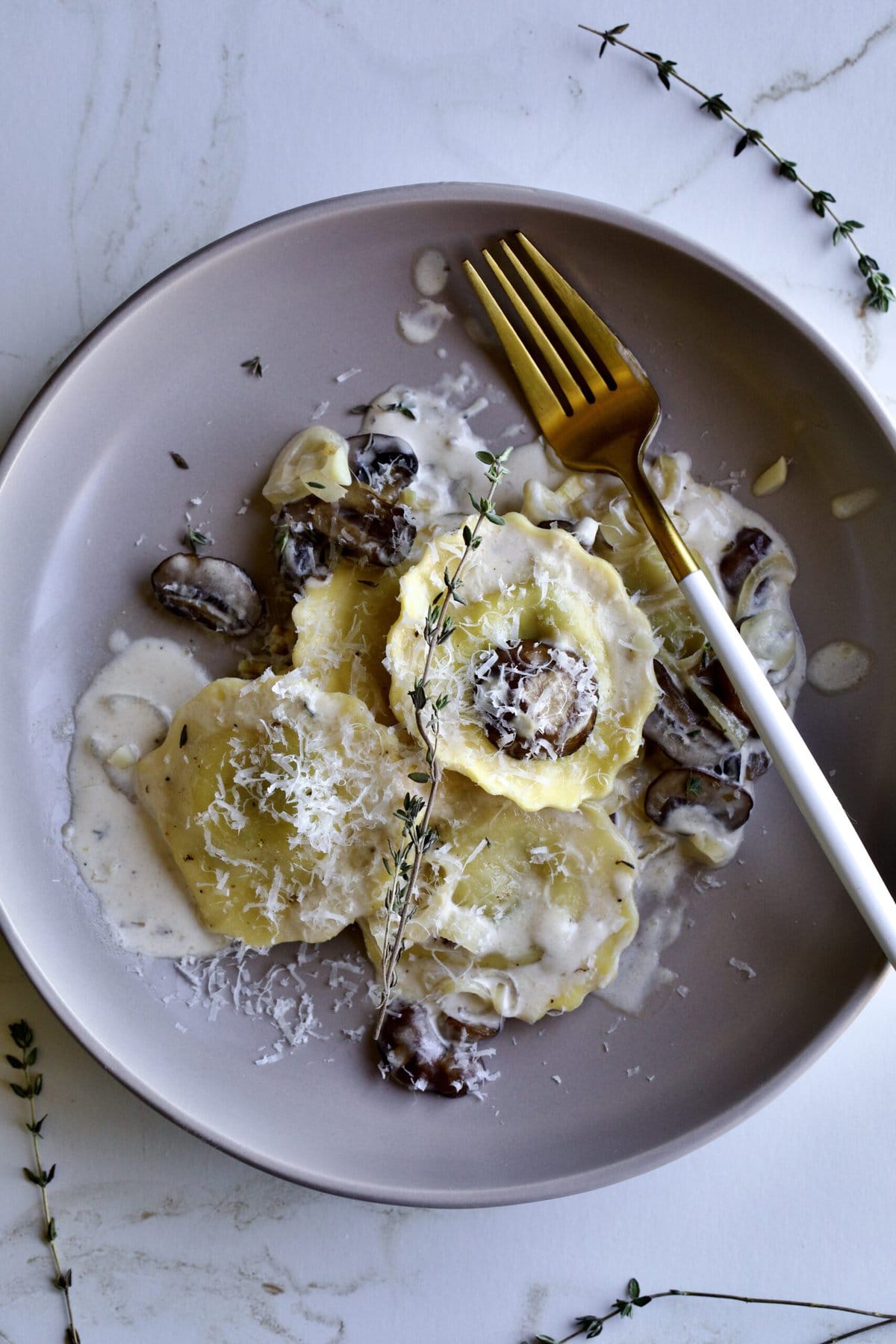 close up of plated ravioli in cream sauce with fork on the plate.