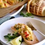one filet of stuffed salmon on a plate with platter of other stuffed salmon on platter.