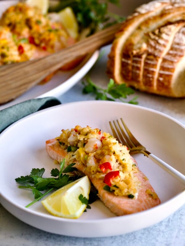 one filet of stuffed salmon on a plate with platter of other stuffed salmon on platter.