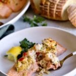one filet of stuffed salmon on a plate with a bite taken out on fork.
