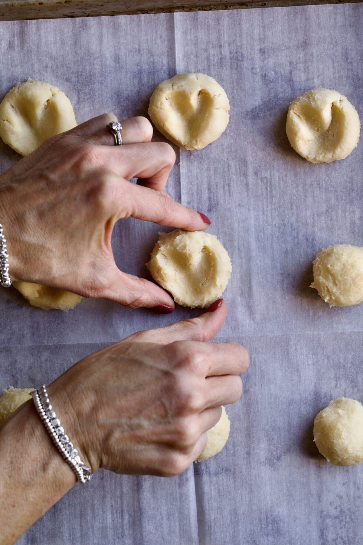 heart shaped cookie dough balls. Thumb pressing into ball to make heart shape. 