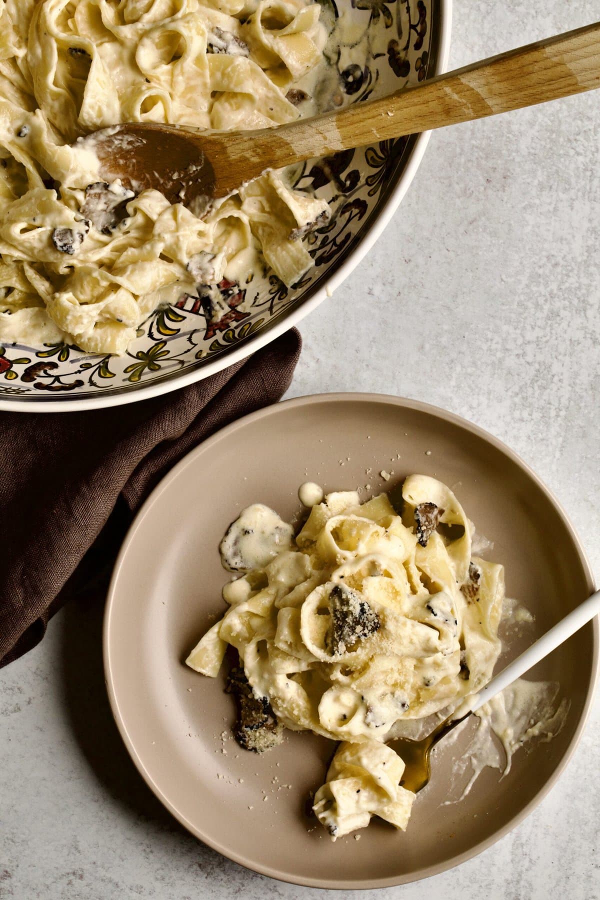 plated black truffle cream sauce pasta with truffle cream sauce on the side.