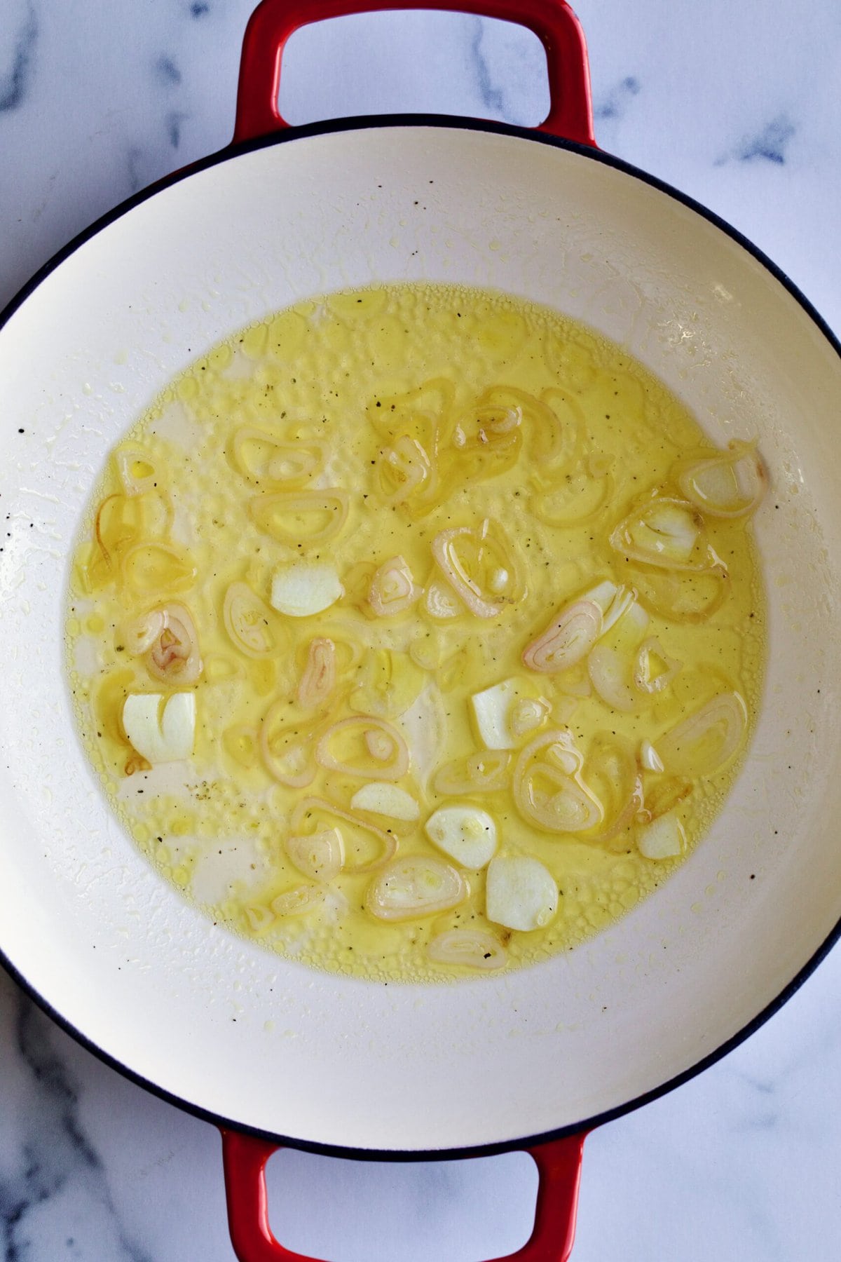 process of making recipe: cooking shallots and garlic in olive oil.