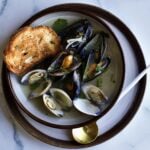Steamed Mussels and Clams Recipe (with Wine and Garlic) in a bowl with spoon and toasted bread.